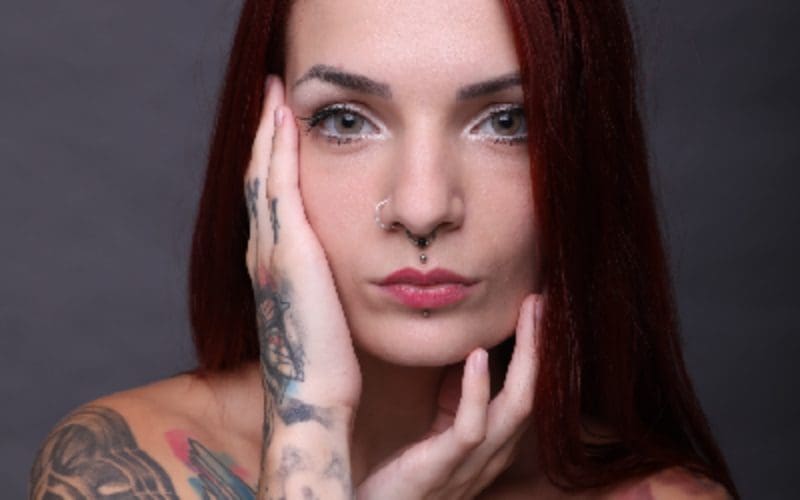 A woman with red hair and tattoos on her face.