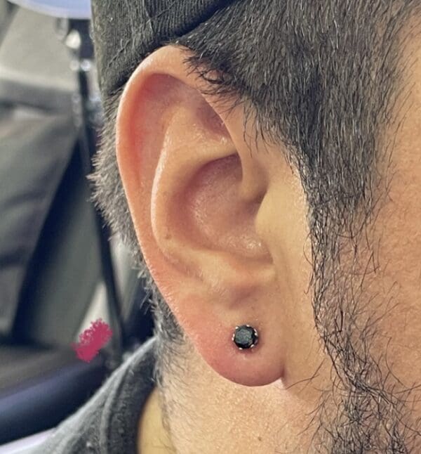 A man with ear piercings and a black earring.