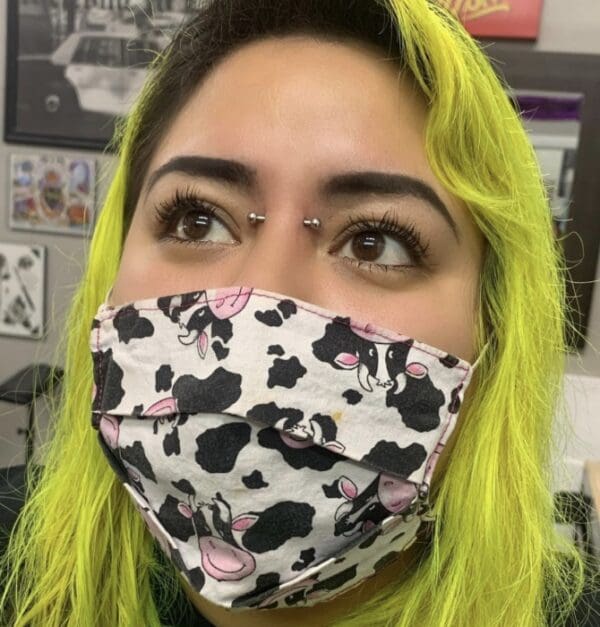 A woman with yellow hair wearing a cow print face mask.