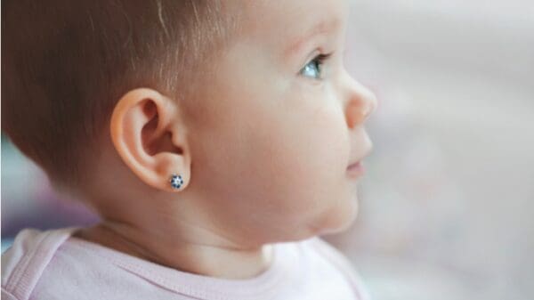 A baby with ear piercings and a white shirt