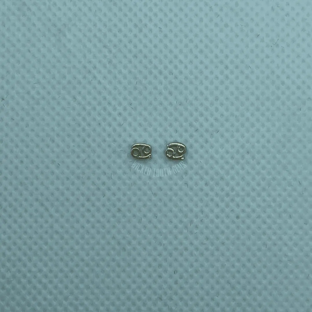 A pair of earrings sitting on top of a blue surface.