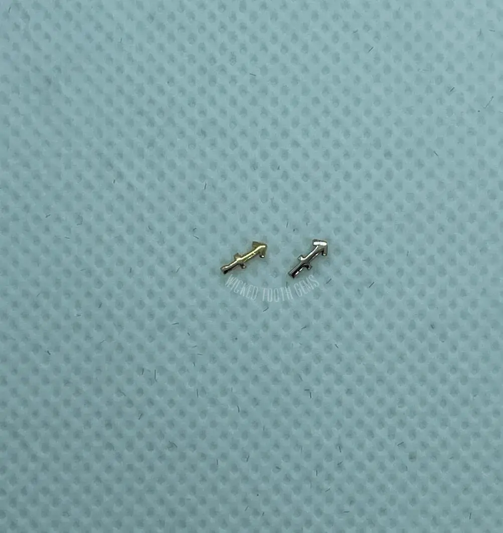 A pair of tiny metal pins sitting on top of a blue surface.