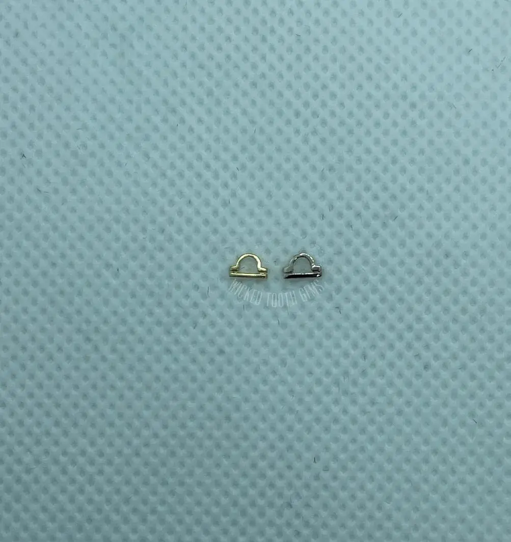 A pair of tiny gold earrings sitting on top of a blue surface.