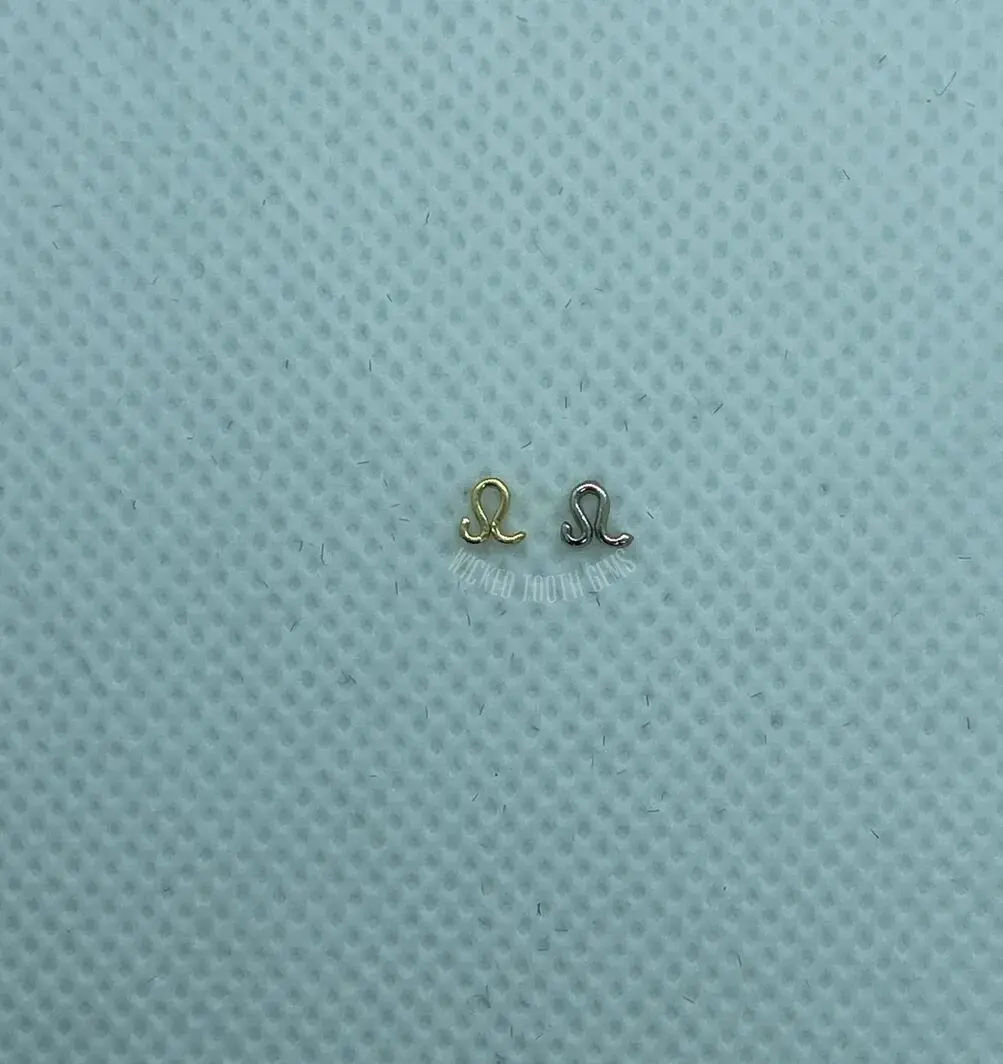 A pair of tiny gold earrings sitting on top of a blue cloth.