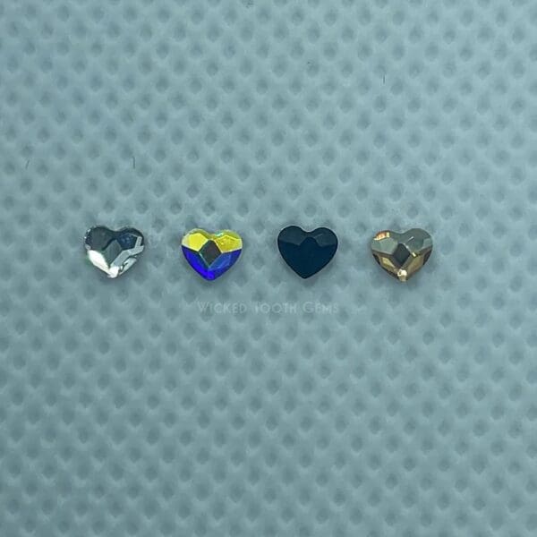 Four different colored hearts are sitting on a blue surface.