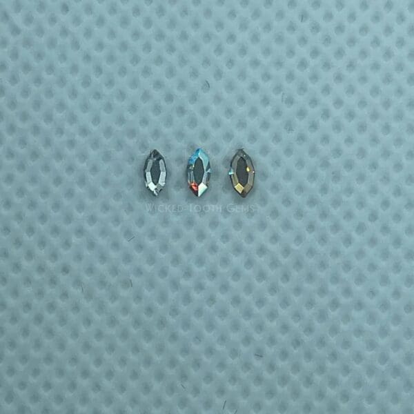 Three different shapes of glass beads on a blue surface.