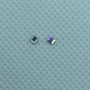 A pair of square shaped earrings sitting on top of a blue surface.