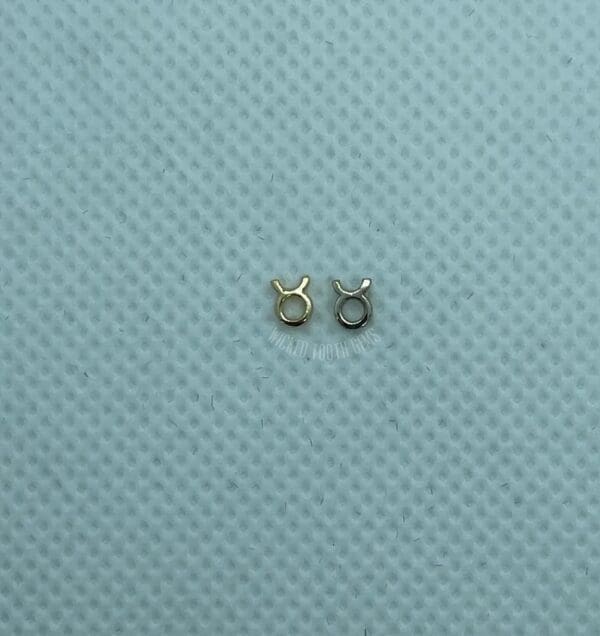 A pair of small silver earrings sitting on top of a blue surface.