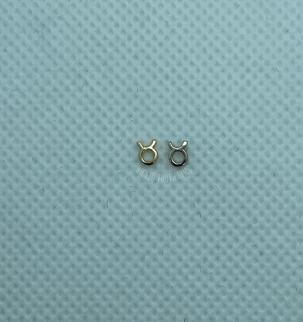 A pair of small silver earrings sitting on top of a blue surface.