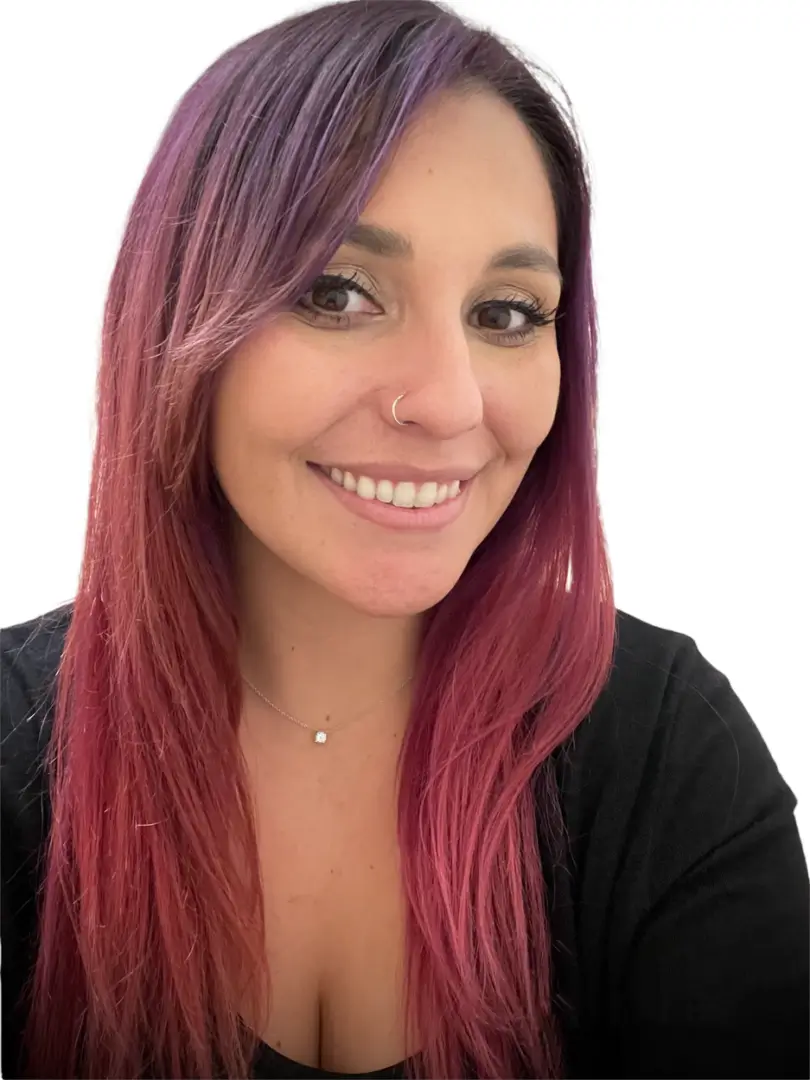 A woman with pink hair smiling for the camera.