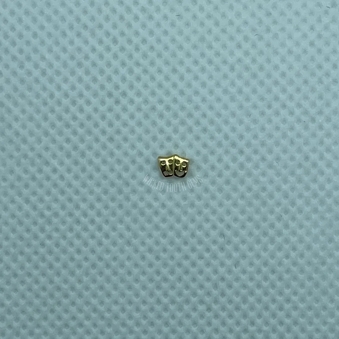 A small gold butterfly sitting on top of a blue surface.