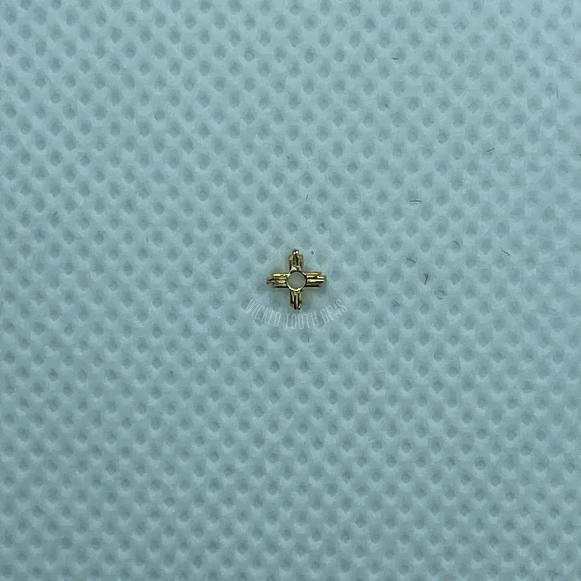 A small gold cross on top of a blue surface.