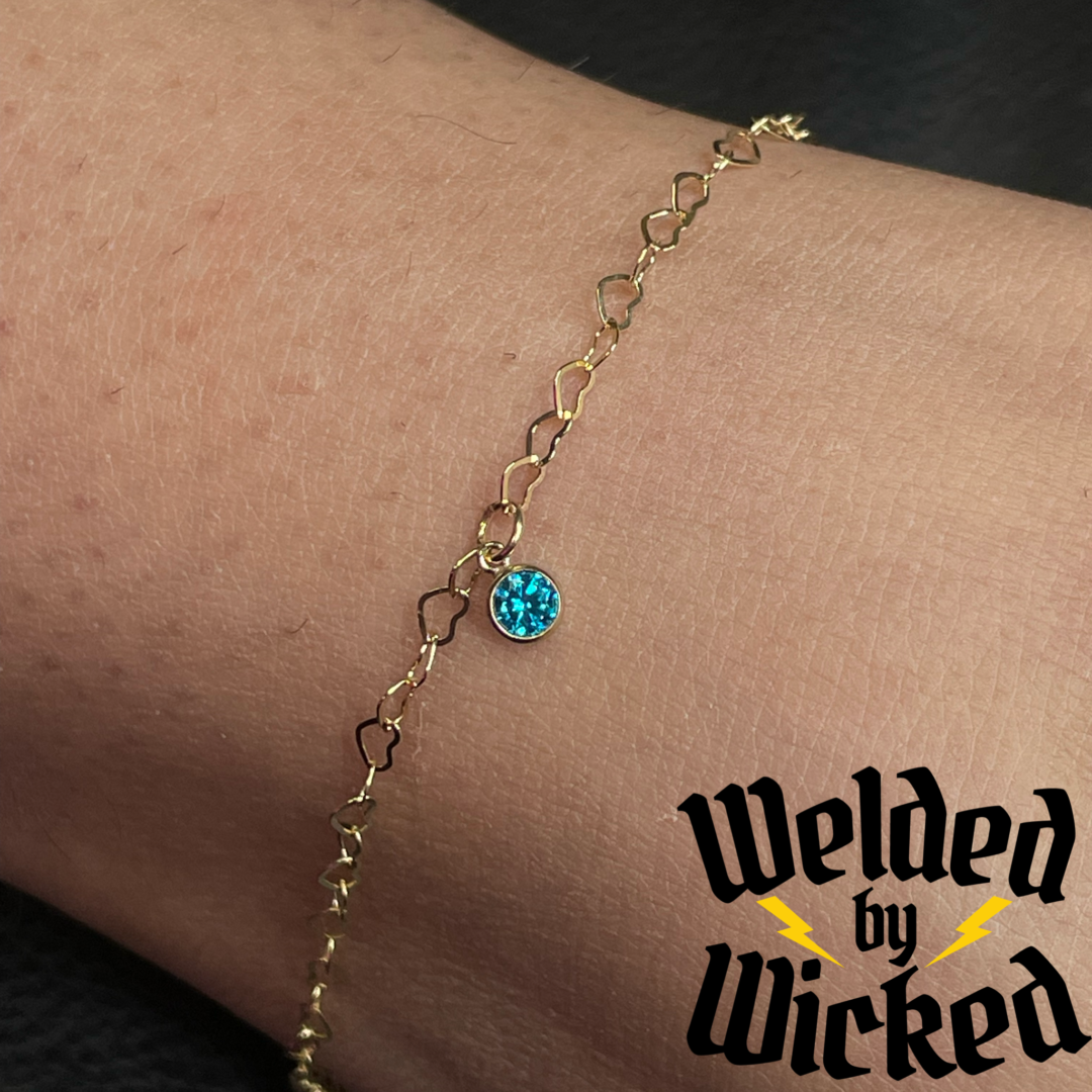 A close up of the anklet with a blue stone