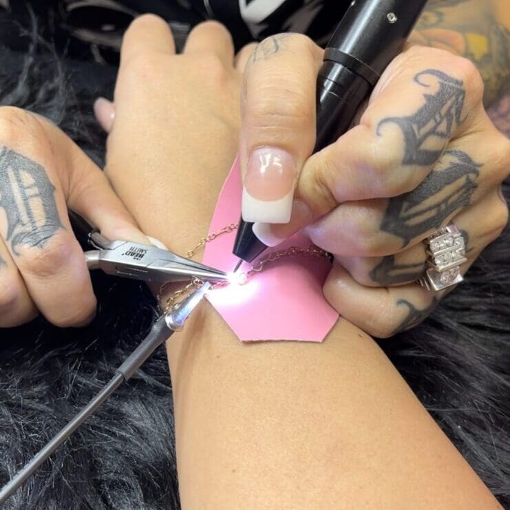 A person is using scissors to cut off the pink strip.