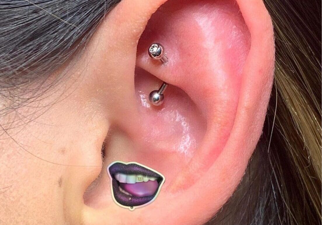 A woman with her ear pierced with two piercings.